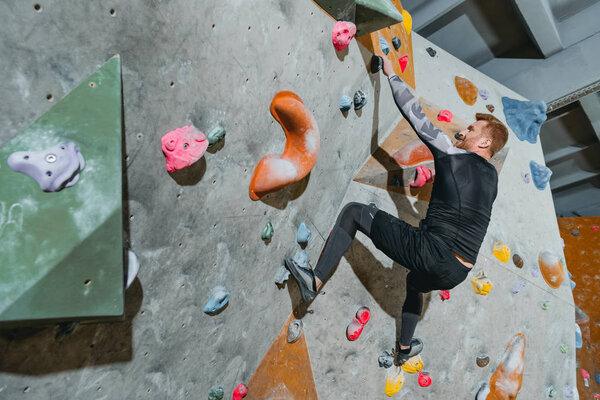 Man climbing wall with grips