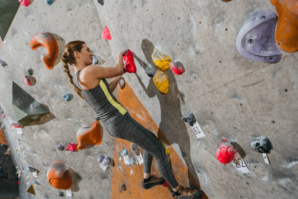 woman climbing wall with grips