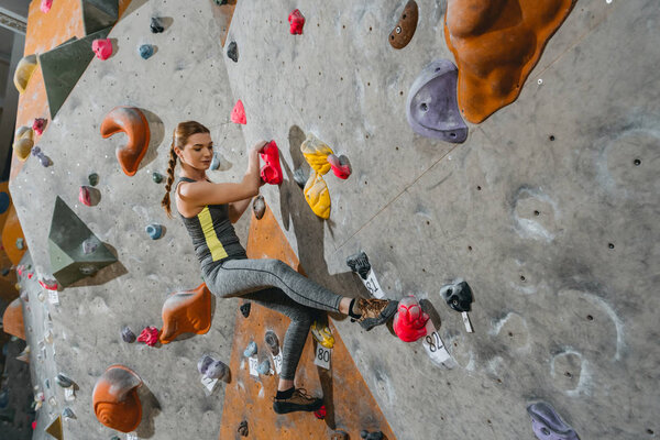 woman climbing wall with grips