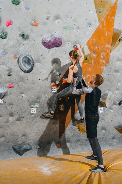 young woman climbing wall with grips