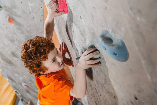 red-headed boy climbing wall