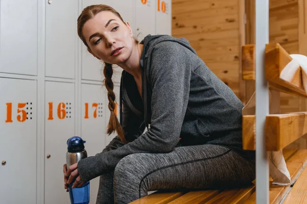 Vrouw zitten op bankje in kleedkamer — Stockfoto