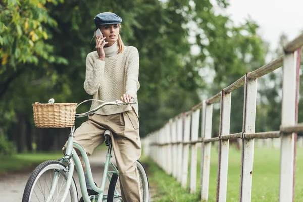 Женщина со смартфоном на велосипеде — стоковое фото
