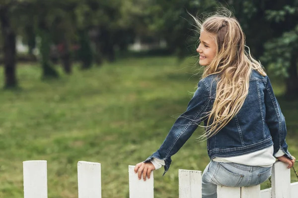 Criança sentada em cerca no campo — Fotografia de Stock