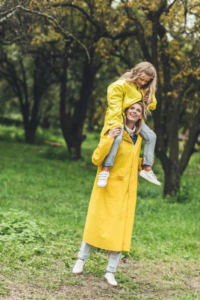 Mother and daughter in raincoats at countryside — Stock Photo, Image