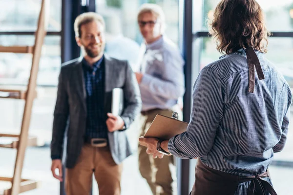 Waiter greeting businessmen in cafe — Stock Photo, Image