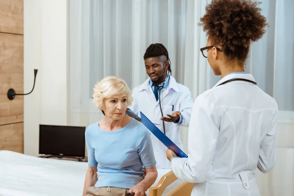 Elderly woman with doctors in hospital — Stock Photo, Image