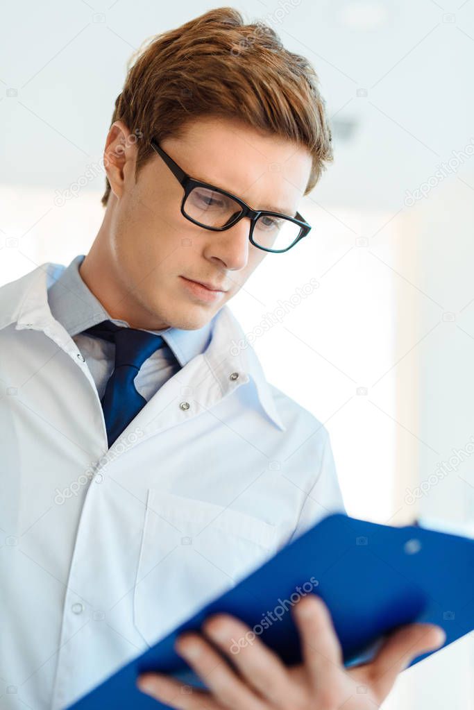 Doctor reading notes on clipboard