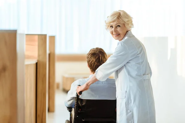 Médecin roulant en fauteuil roulant avec patient — Photo