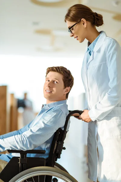 Lekarz toczenia człowiek na wózku inwalidzkim — Zdjęcie stockowe