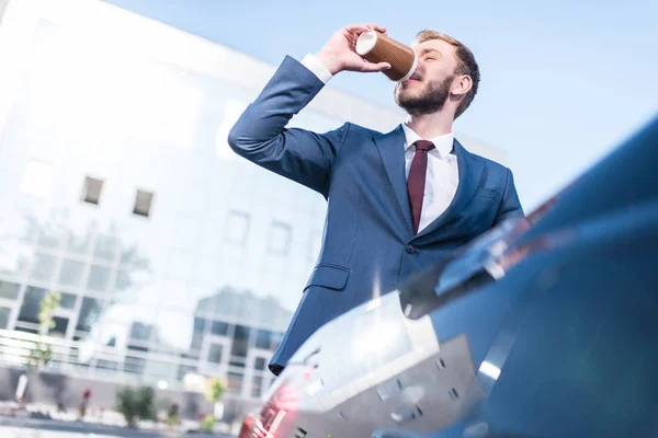 Businessman drinking coffee at car — Free Stock Photo