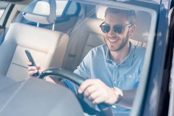 Man with smartphone driving car — Stock Photo, Image