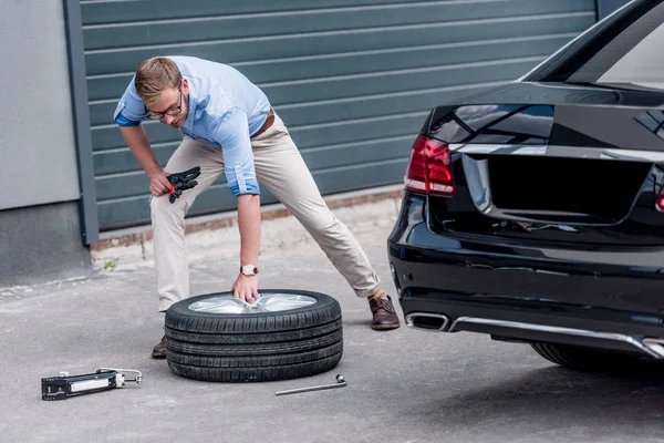 Hombre cambiando neumático de coche — Foto de Stock