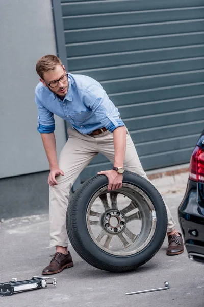 Hombre cambiando neumático de coche — Foto de Stock