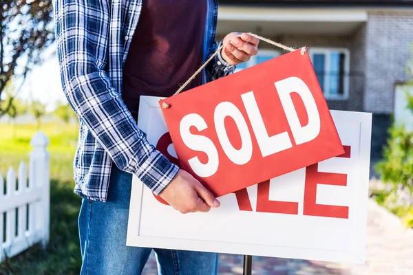 Man hanging sold sign — Stock Photo, Image