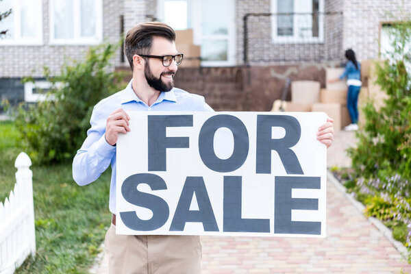 realtor with banner for sale