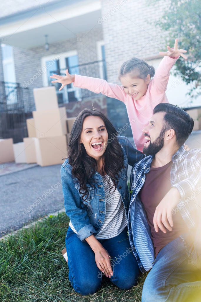 Beautiful family having fun together outdoors while sitting on grass