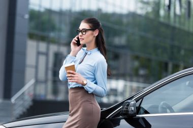 businesswoman talking on smartphone with coffee