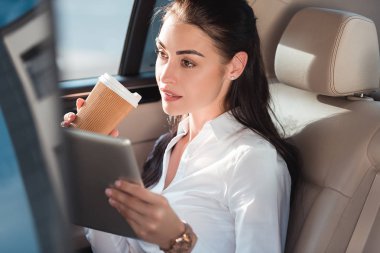 woman in car with digital tablet and coffee clipart