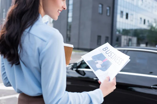 Woman holding business newspaper and coffee — Stock Photo, Image