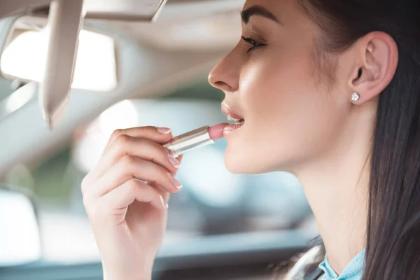 Mujer aplicando lápiz labial en el coche — Foto de Stock