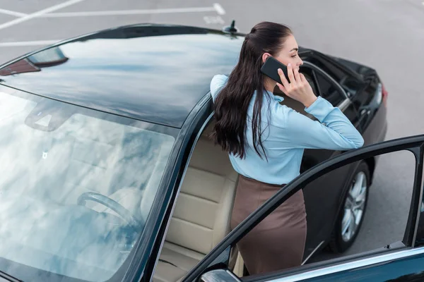 Zakenvrouw praten over smartphone in de buurt van auto — Stockfoto