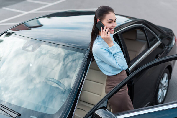 business woman talking on smartphone near car

