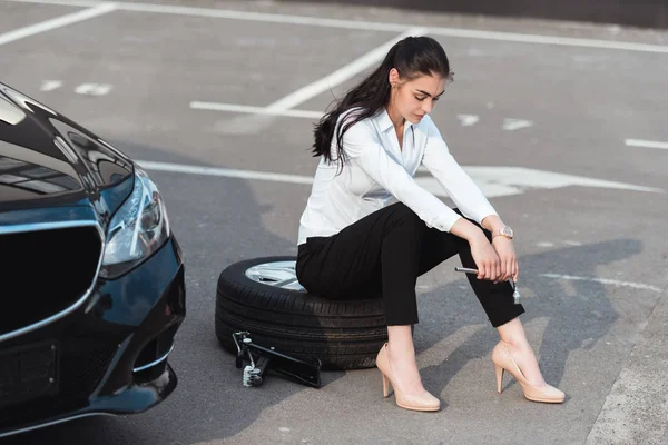 Женщина сидит на шине с гаечным ключом — стоковое фото