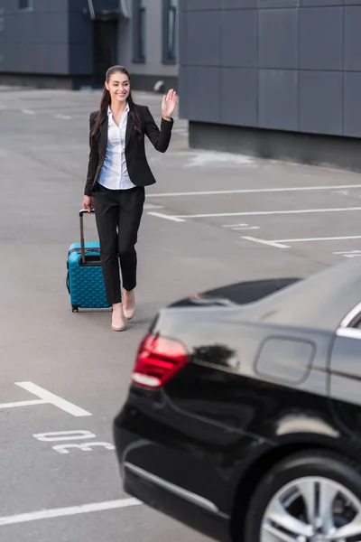 Mulher caminhando com mala no estacionamento — Fotografia de Stock