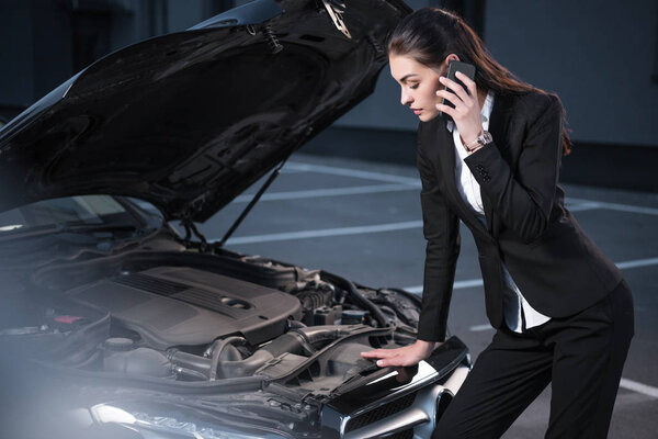 woman looking under hood of car