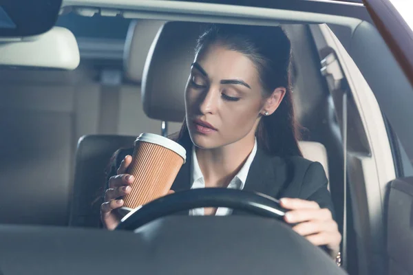 Женщина за рулем и пьет кофе — стоковое фото