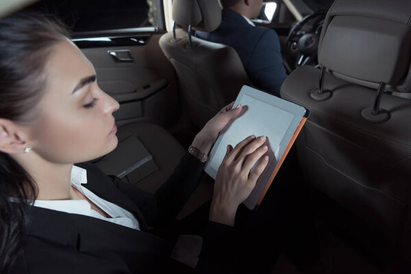 woman in passenger seat using tablet