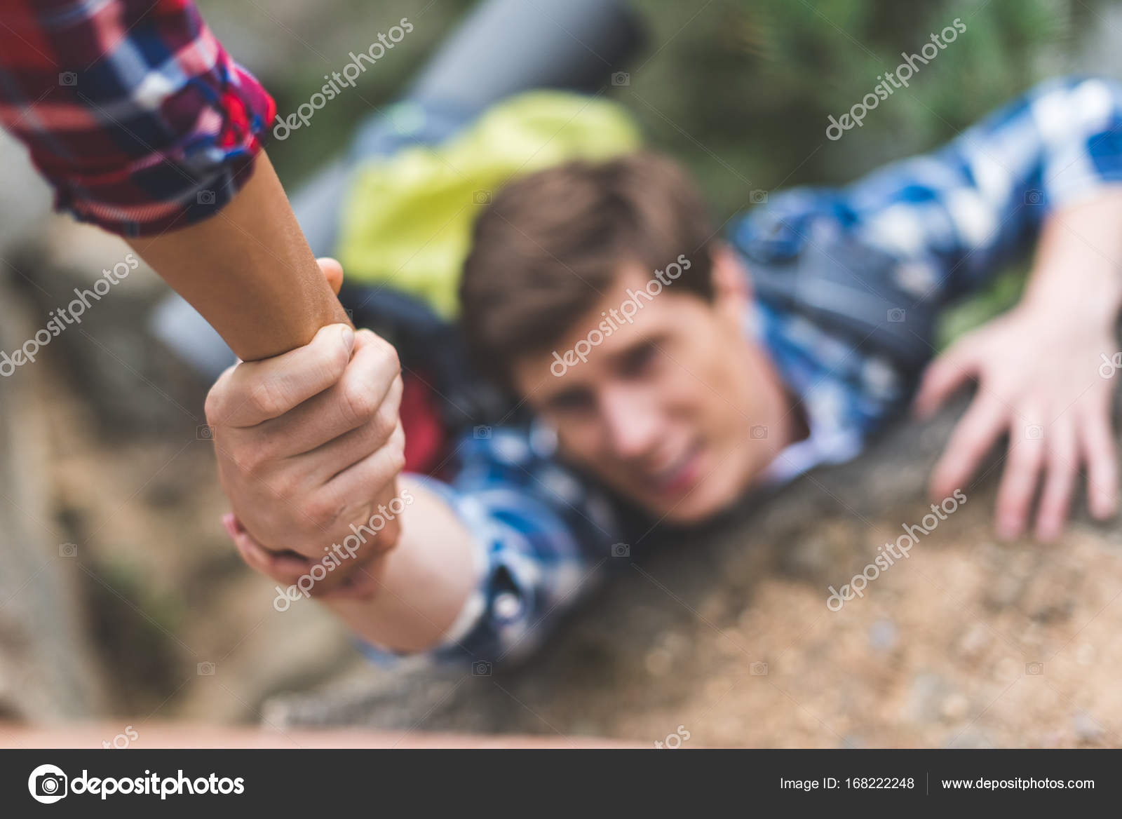 Woman helping boyfriend to climb rock — Stock Photo