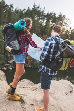 couple with backpacks looking at map