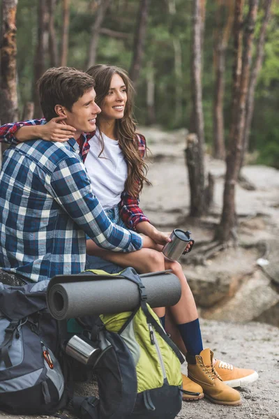 Casal com mochilas relaxantes na floresta — Fotografia de Stock