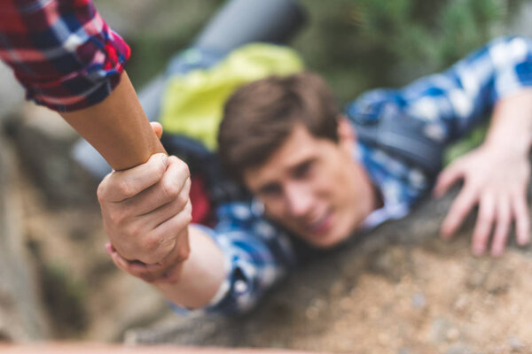 woman helping boyfriend to climb rock