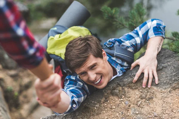 Woman helping boyfriend to climb rock — Stock Photo, Image