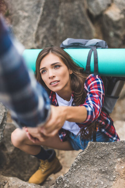 man helping girlfriend to climb rock