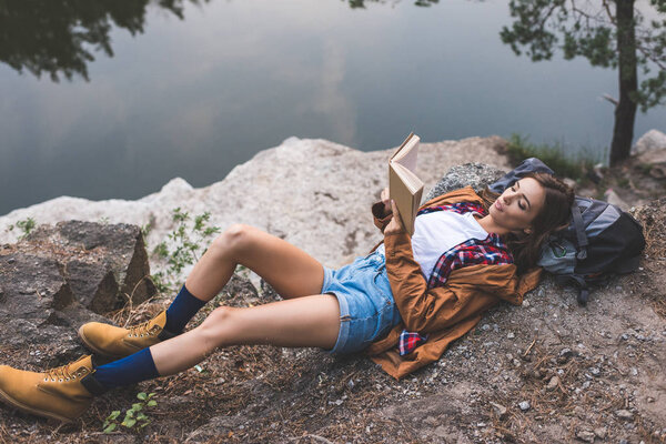 woman reading book on nature