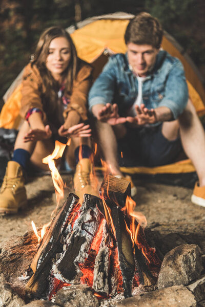 couple warming hands with bonfire