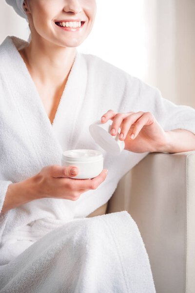 woman opening jar of cream