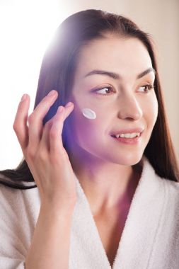 Woman applying face cream clipart
