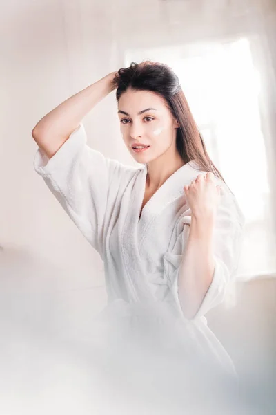 Woman in bathrobe with cream on face — Stock Photo, Image