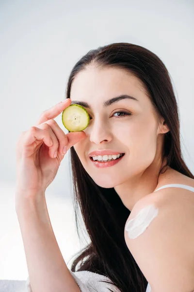 Mulher segurando fatia de pepino no olho — Fotografia de Stock