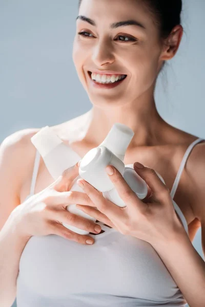 Mujer sonriente sosteniendo recipientes cosméticos —  Fotos de Stock