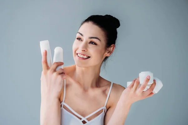 Mulher sorridente segurando recipientes cosméticos — Fotografia de Stock