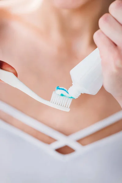 Woman squeezing toothpaste on brush — Stock Photo, Image