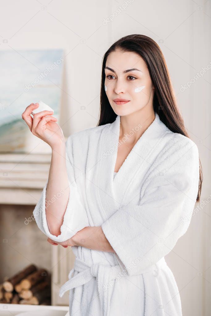 woman holding jar of face cream