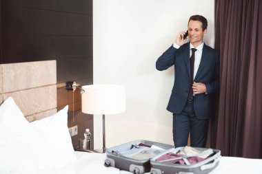 Otel odasında telefonda konuşan işadamı