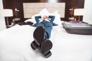 Exhausted businessman lying on bed clipart